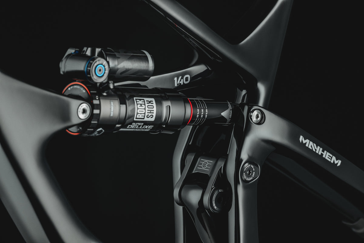Mayhem 140 in Liquid Black — Rear shock and rocker link at the seat tube, seatstay decal beyond
